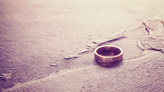 Vintage toned single weeding ring on stone background, conceptual picture.