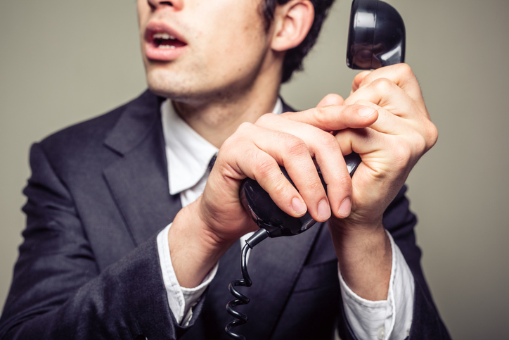 Businessman is covering the phone to speak in private to someone in the room